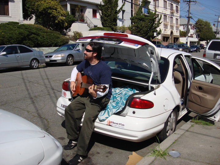 mike sitting in the back of his car playing guitar